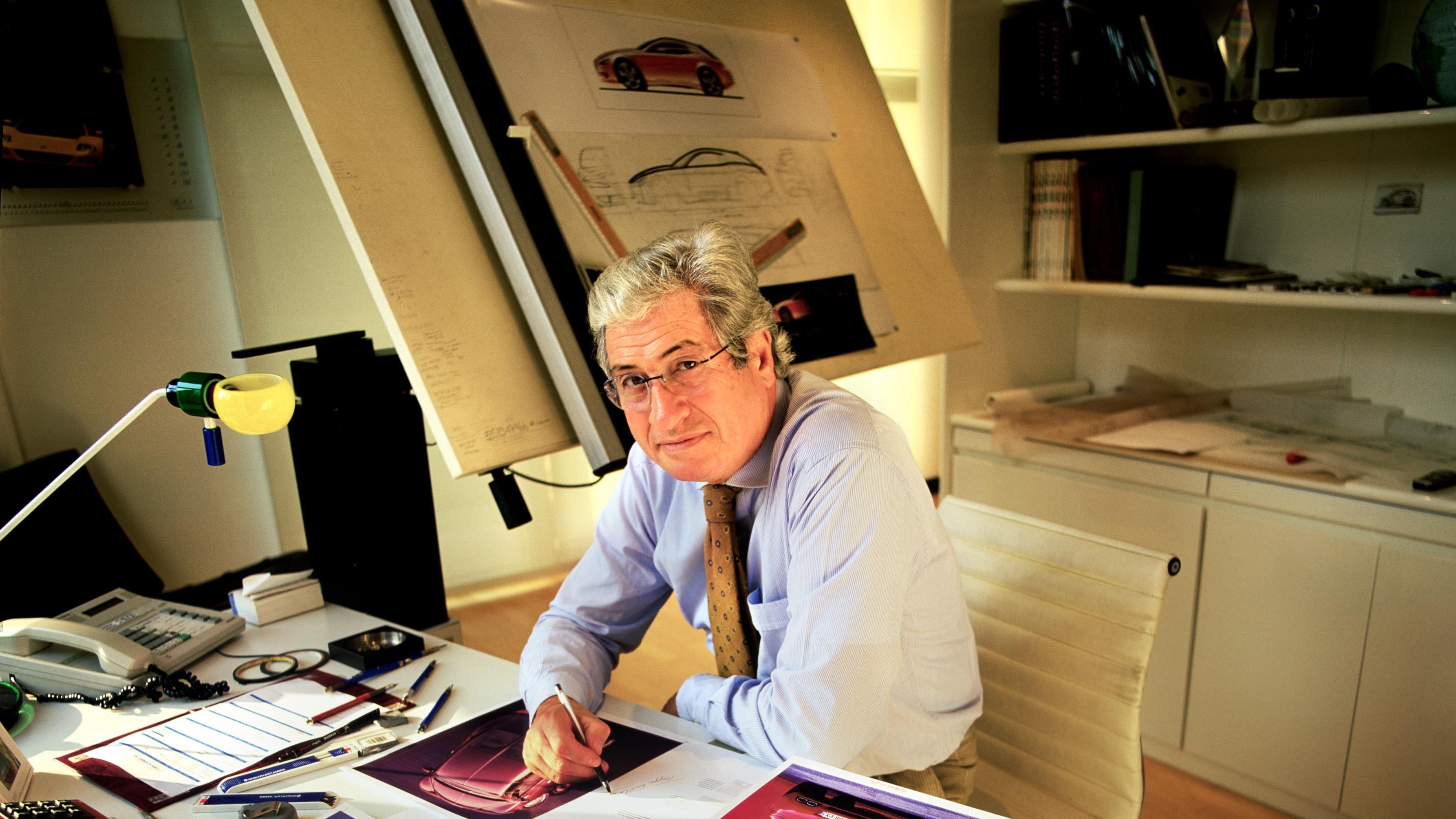 A man works on car designs at a desk.