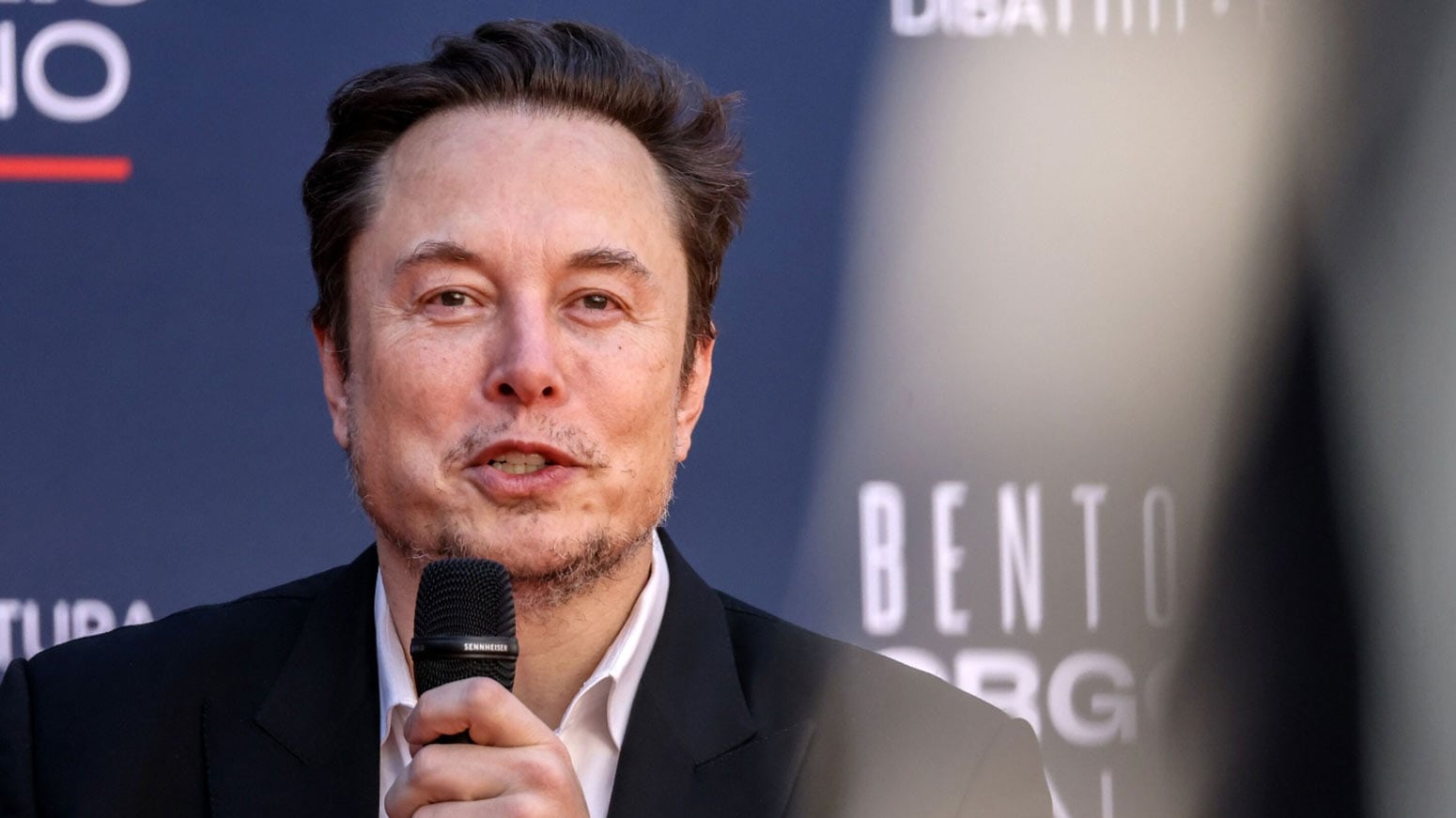 A picture of Elon Musk talking into a microphone.